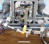 Zwei Roboterarme mit Greifern schälen eine Banane